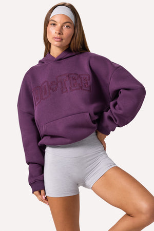 Bo+Tee model Lydia Butler wearing the CosyCoffeeRunWithLydsButler Hoodie in Plum Brushback sweat fabric perfect for casual weekend strolls