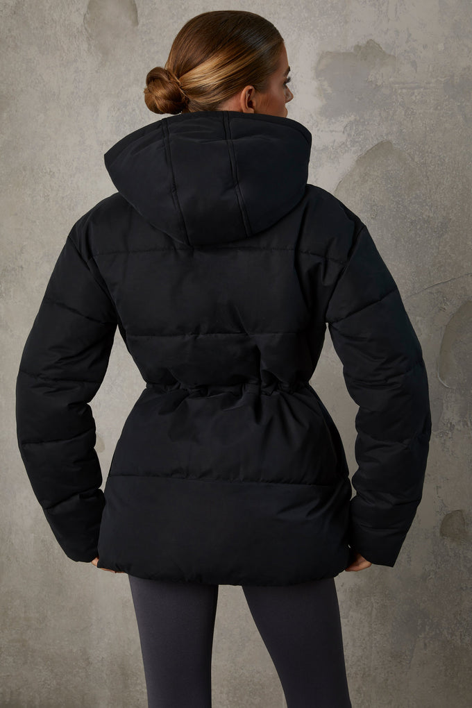 Abrigo acolchado con capucha de longitud media en negro