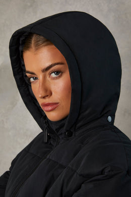 Abrigo acolchado con capucha de longitud media en negro